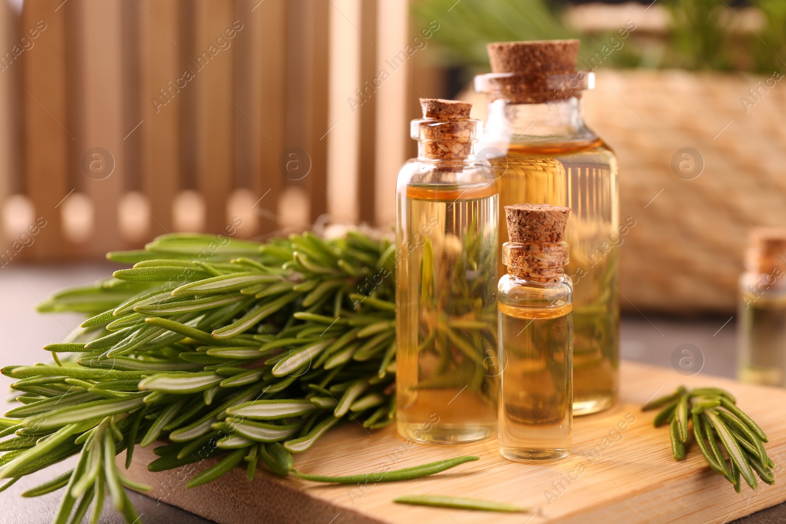 Photo of Essential oil in bottles and rosemary on table, closeup