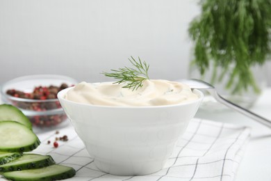 Photo of Tasty creamy dill sauce in bowl on white kitchen towel, closeup