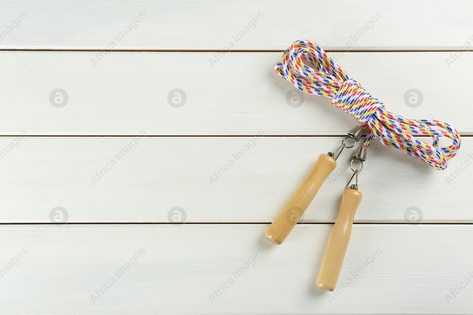 Photo of Skipping rope on white wooden table, top view. Space for text