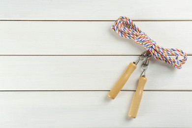 Skipping rope on white wooden table, top view. Space for text