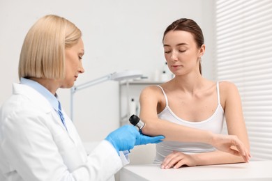 Photo of Dermatologist with dermatoscope examining patient in clinic