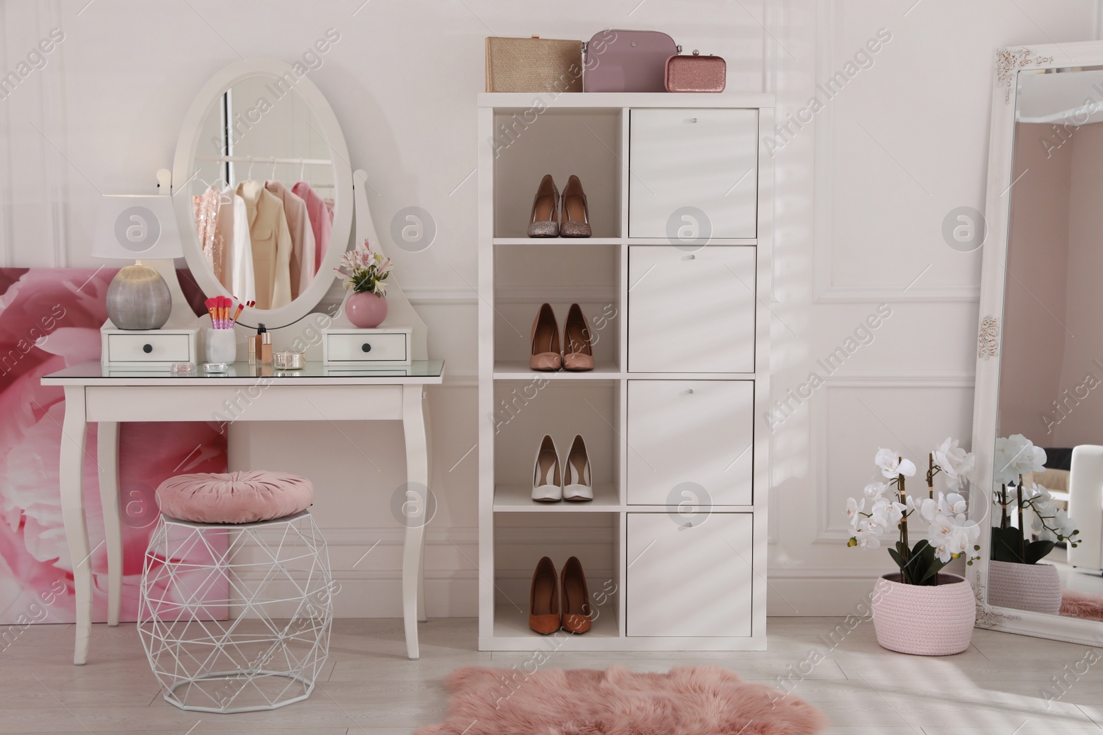Photo of Stylish dressing room interior with shelving unit, table and mirror