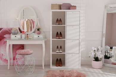 Stylish dressing room interior with shelving unit, table and mirror