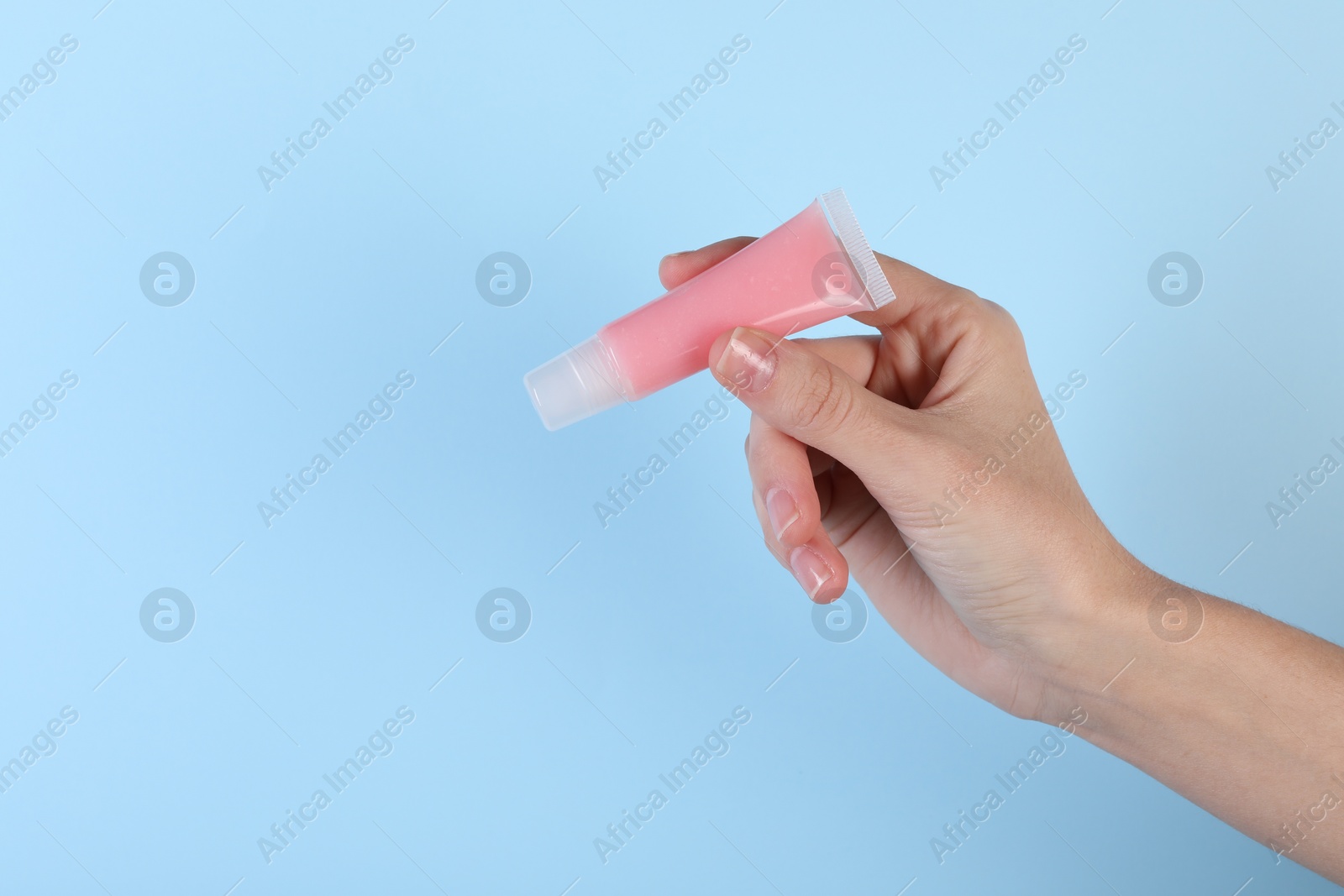 Photo of Woman with lip balm on light blue background, closeup