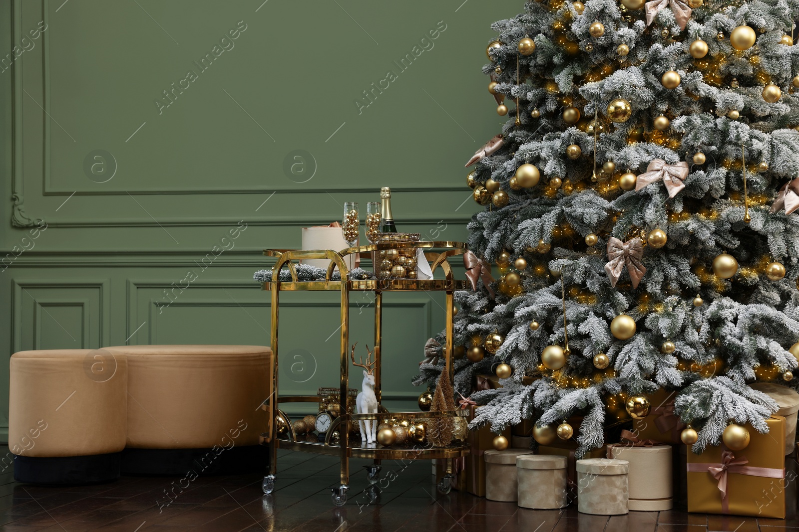 Photo of Beautiful Christmas tree, gift boxes, table and festive decor near olive wall indoors. Interior design