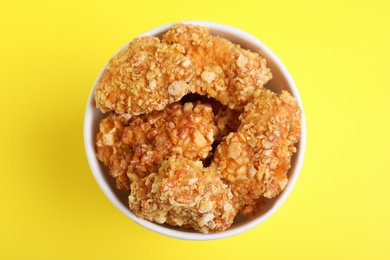 Photo of Bucket with yummy nuggets on yellow background, top view