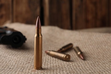 Photo of Many brass bullets on burlap, closeup. Space for text