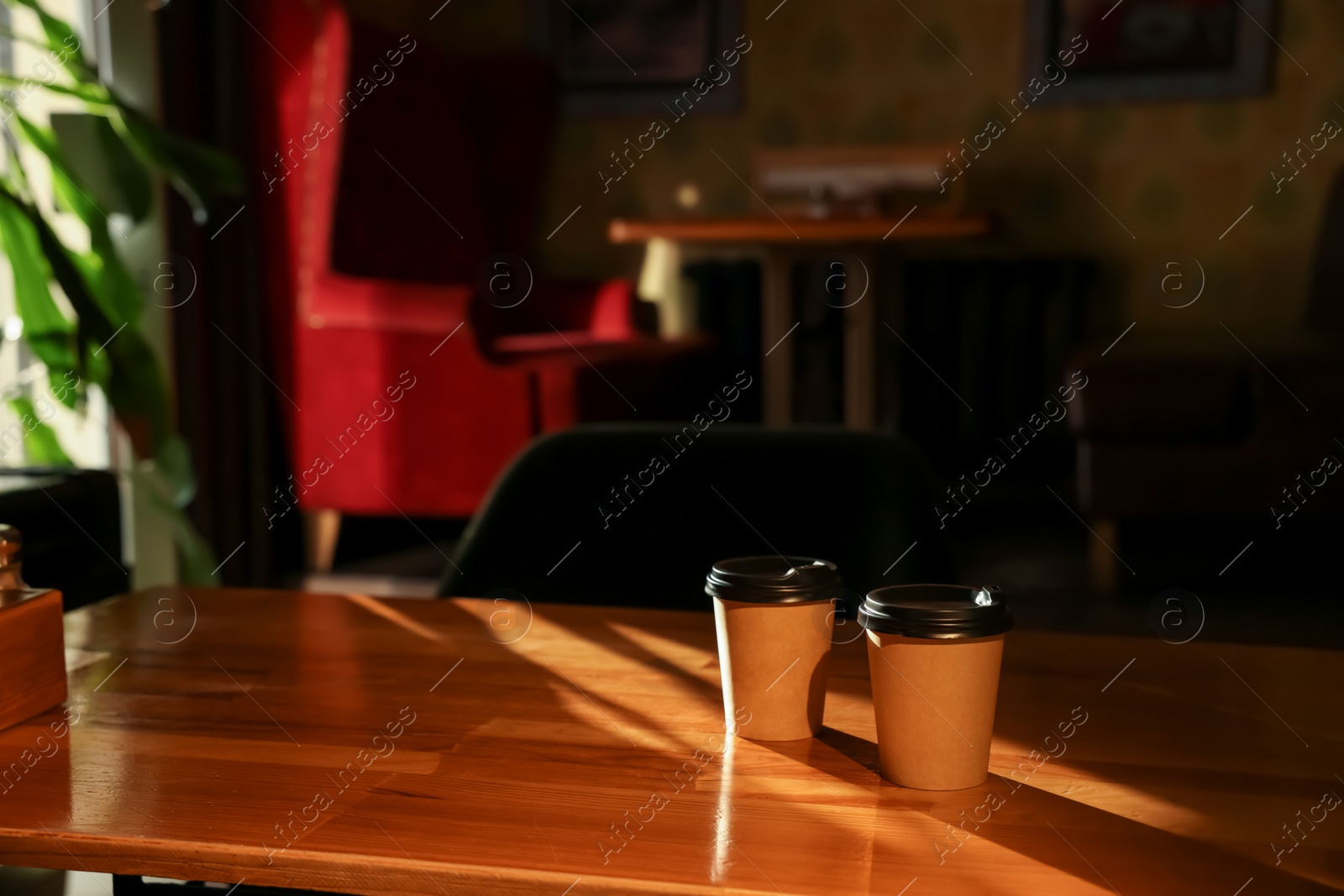 Photo of Paper coffee cups on wooden table in cafe. Space for text