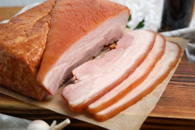 Photo of Delicious smoked bacon on wooden board, closeup