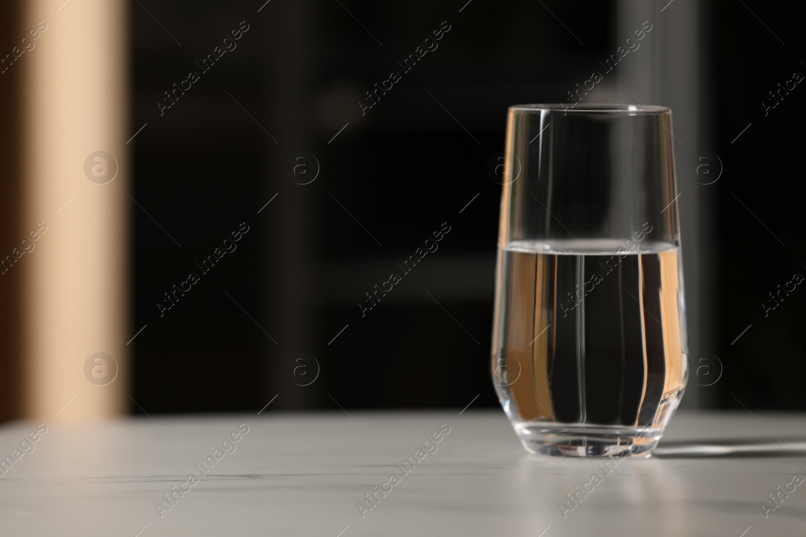 Photo of Glass of pure water on white table indoors, space for text