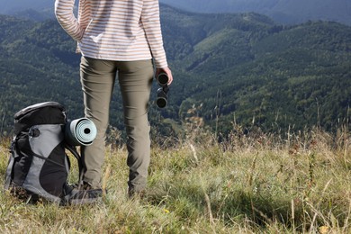 Photo of Back view of tourist with hiking equipment and binoculars in mountains, closeup