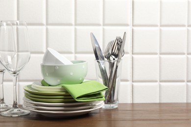 Beautiful ceramic dishware, glasses and cutlery on wooden table, space for text