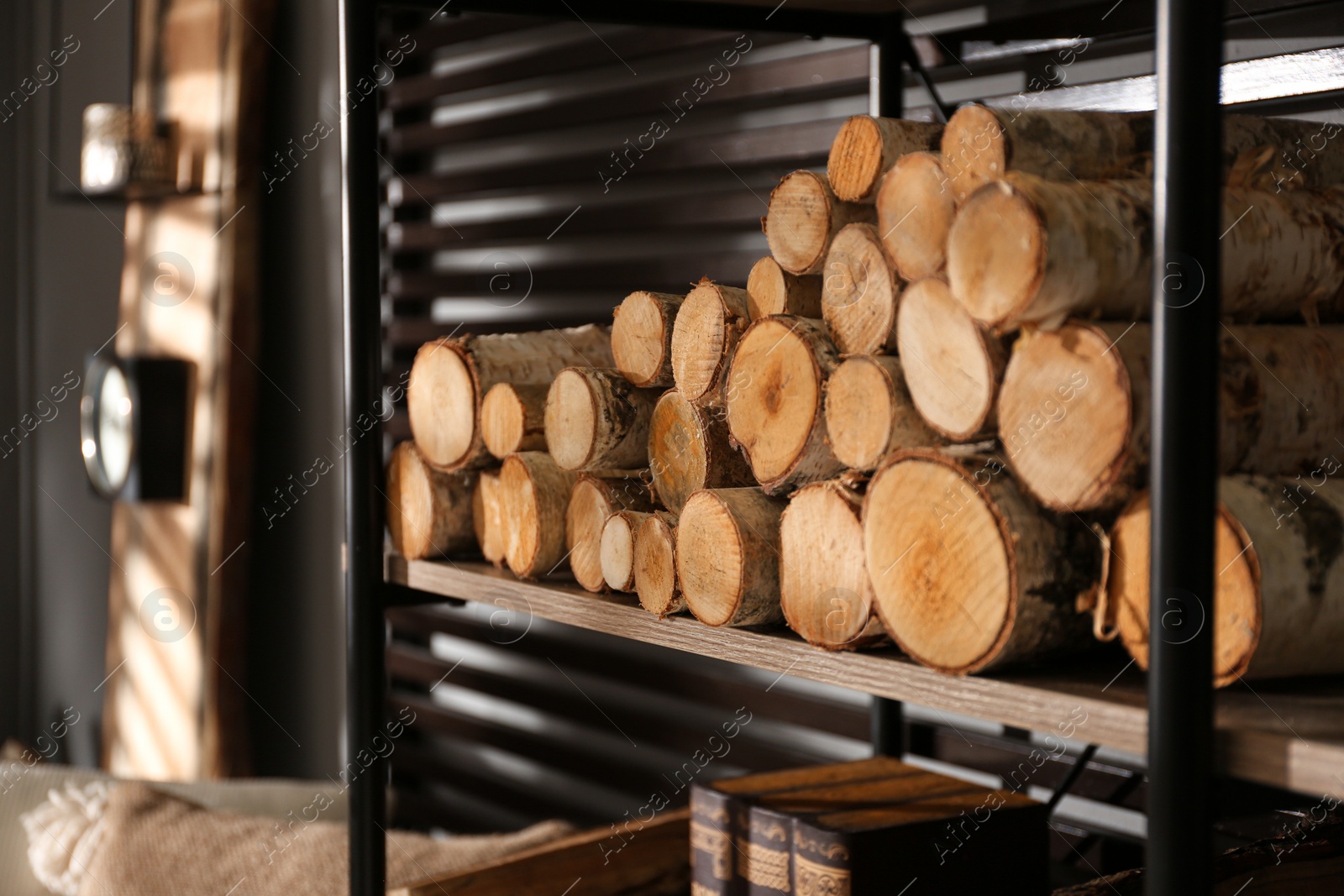 Photo of Shelving unit with stacked firewood near wall in room, closeup. Idea for interior design