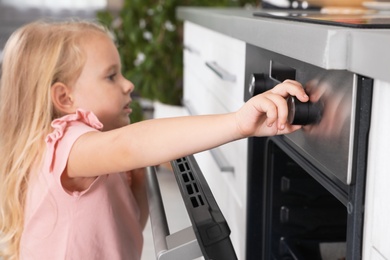 Photo of Little girl baking something in oven at home