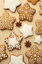 Tasty Christmas cookies with icing and anise stars on beige background, flat lay