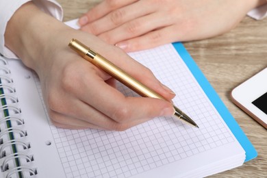 Photo of Woman taking notes at wooden table, closeup