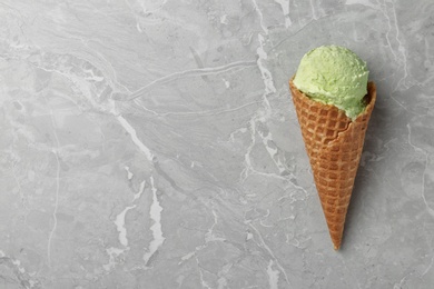 Photo of Delicious pistachio ice cream on grey marble table, top view. Space for text