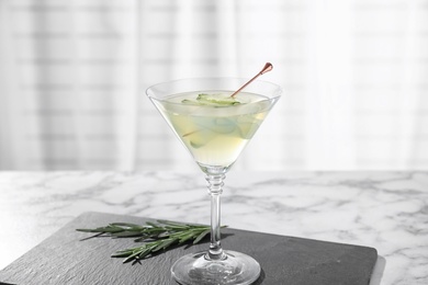Glass of tasty cucumber martini on white marble table