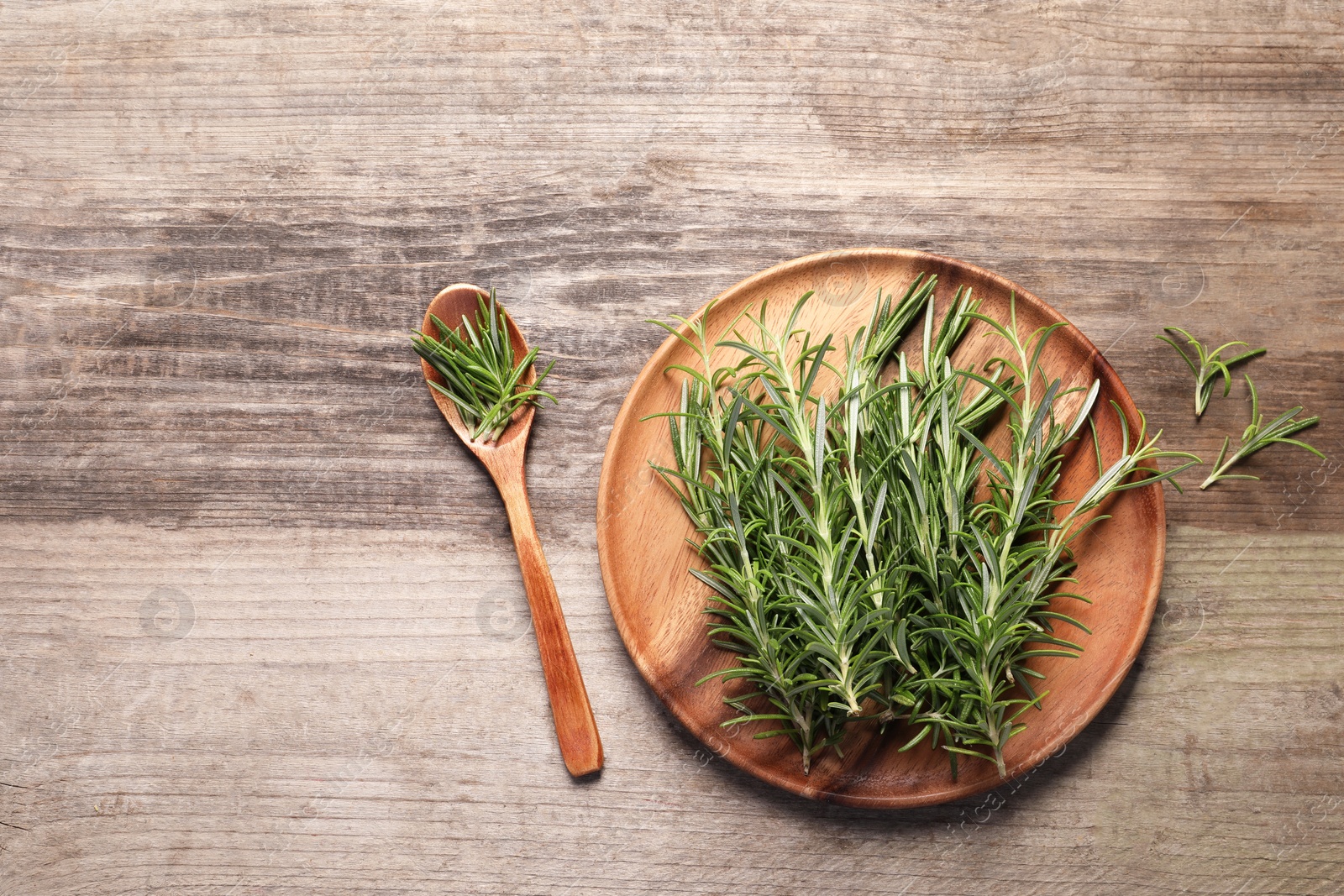 Photo of Fresh rosemary sprigs on wooden table, flat lay. Space for text