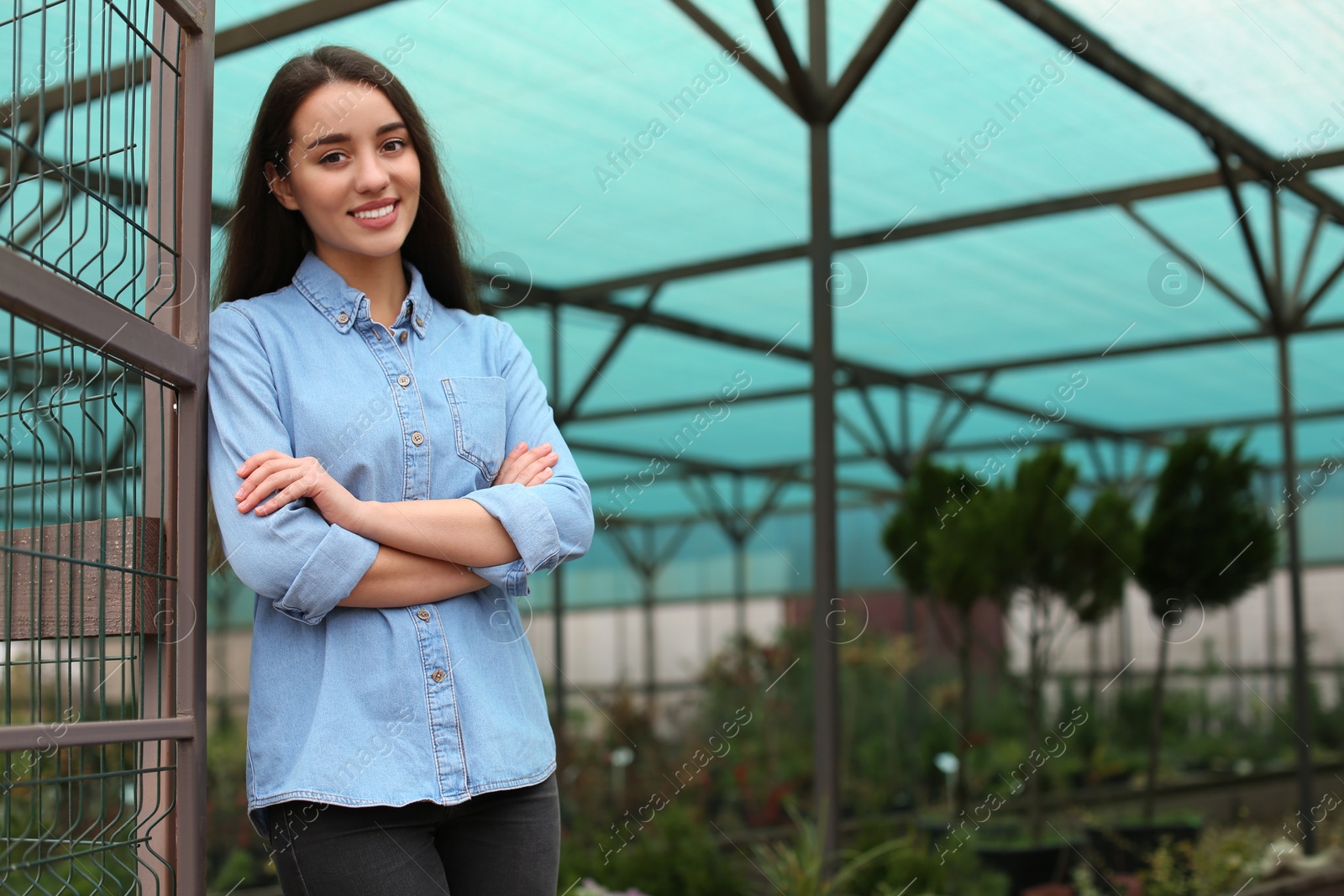 Photo of Female business owner in greenhouse. Space for text