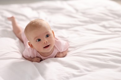 Cute little baby lying on white sheets, space for text