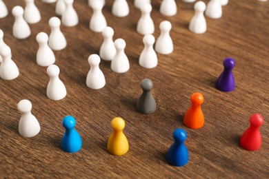 Photo of Colorful pawns on wooden table. Social inclusion concept