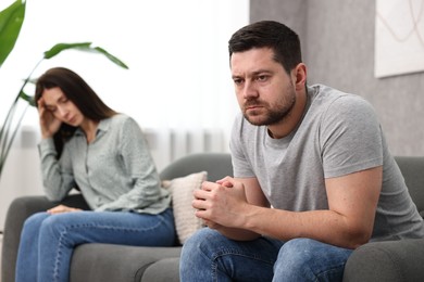 Photo of Offended couple ignoring each other after quarrel indoors, selective focus. Relationship problems