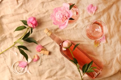 Photo of Flat lay composition with rose wine and beautiful peonies on beige fabric