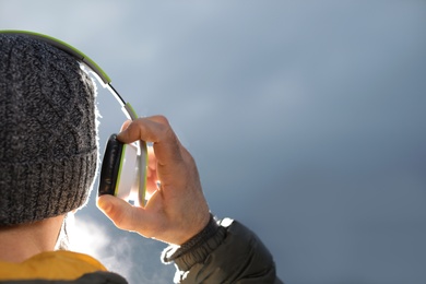 Man with headphones listening to music on blurred background, space for text