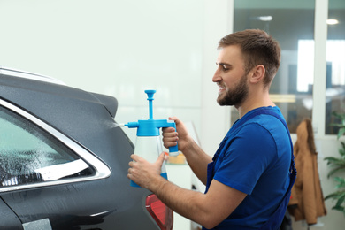 Photo of Worker spraying water onto car window before tinting