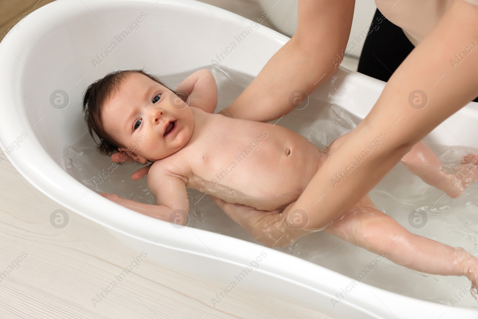 Photo of Mother bathing her little baby in bathtub, closeup