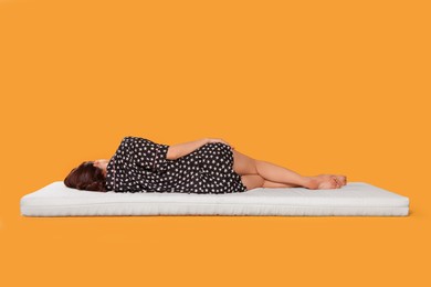 Photo of Young woman sleeping on soft mattress against orange background, back view