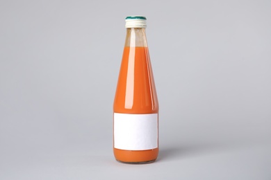 Photo of Tasty drink in bottle with blank label on color background. Mock up for design