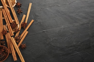 Photo of Aromatic cinnamon sticks and anise on black table, flat lay. Space for text