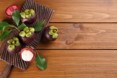 Photo of Fresh ripe mangosteen fruits on wooden table, flat lay. Space for text