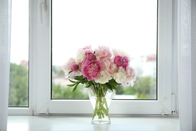 Photo of Beautiful peony bouquet in vase on windowsill indoors