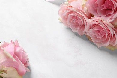 Photo of Beautiful roses on light pink marble table, space for text. Happy birthday greetings