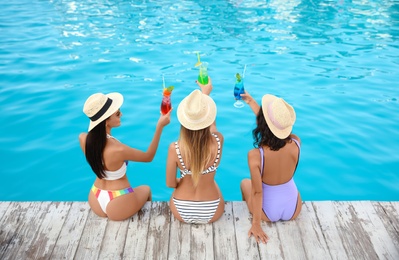 Group of friends with refreshing cocktails near outdoor swimming pool