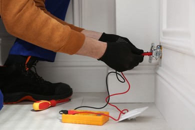 Electrician with tester checking voltage indoors, closeup