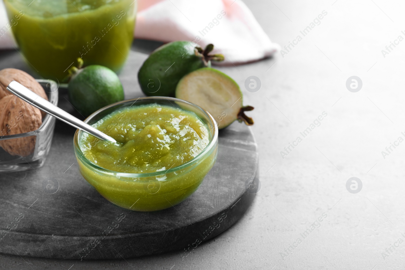 Photo of Feijoa jam in glass bowl on grey table. Space for text