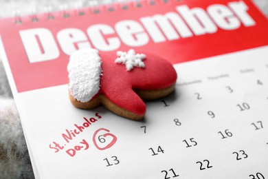 Photo of Saint Nicholas Day. Calendar with marked date December 06 and glove shape gingerbread cookie, closeup