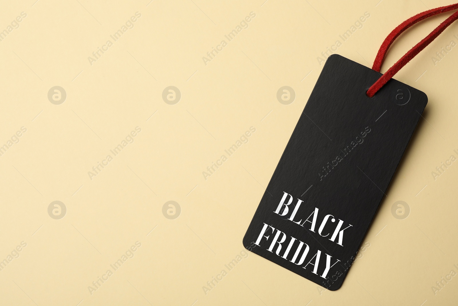 Image of Tag with phrase BLACK FRIDAY on beige background, top view. Space for text
