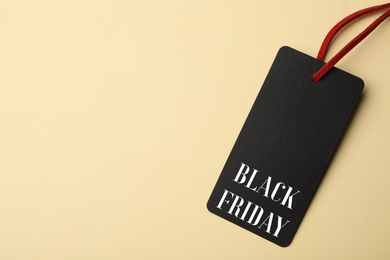 Image of Tag with phrase BLACK FRIDAY on beige background, top view. Space for text