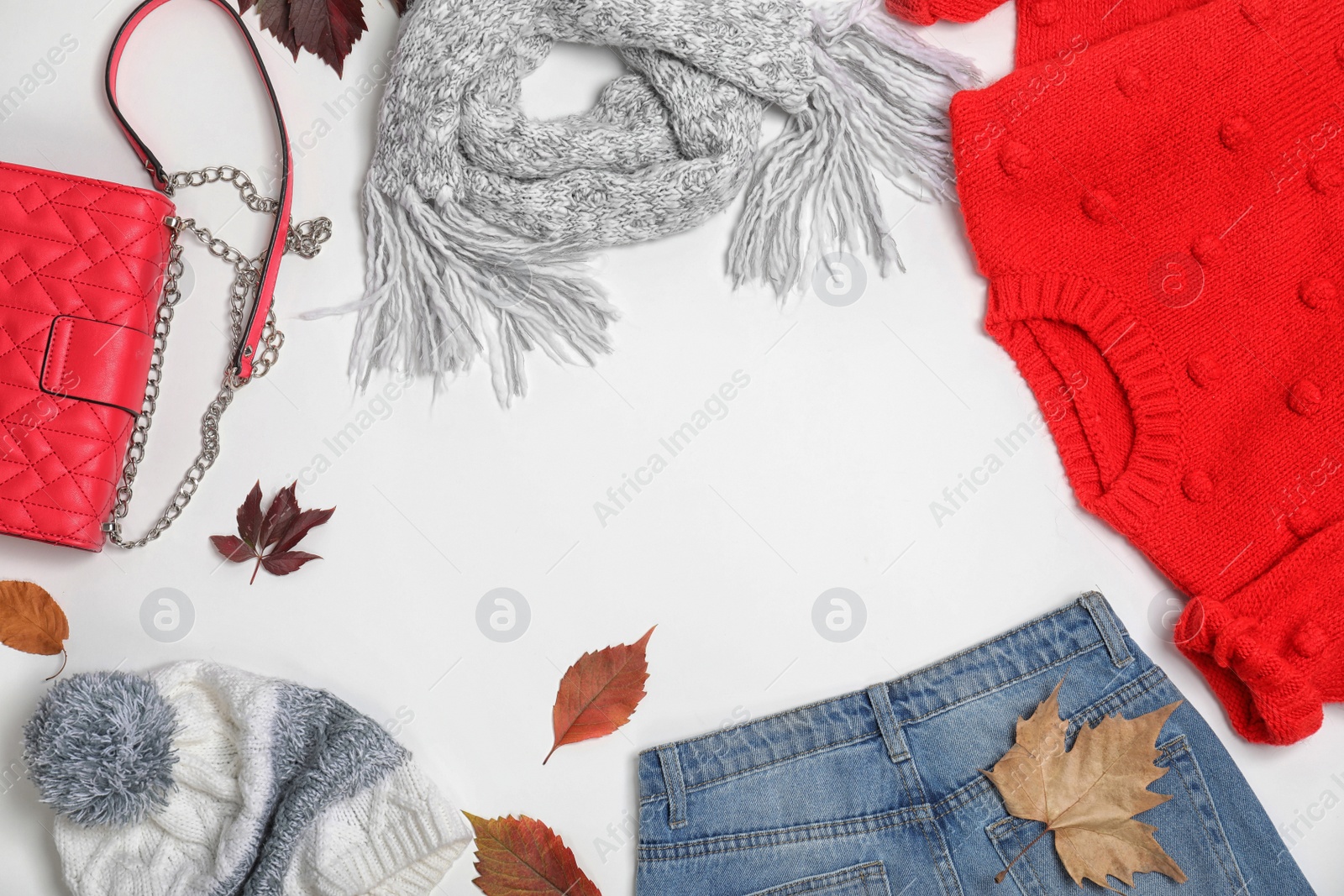 Photo of Stylish outfit and autumn leaves on white background, top view with space for text. Trendy warm clothes