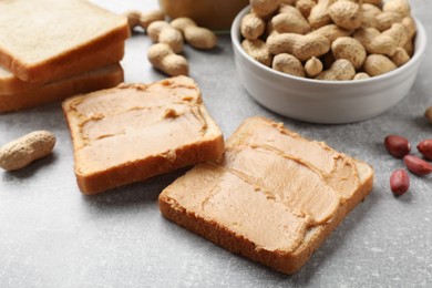 Photo of Tasty peanut butter sandwiches and peanuts on gray table, closeup