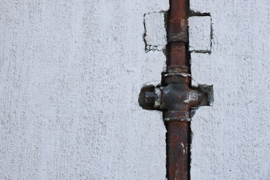 Photo of Rusty gas pipe installed in white wall outdoors, space for text