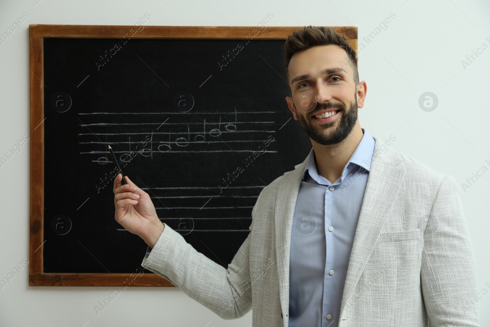 Photo of Teacher near black chalkboard with music notes in classroom