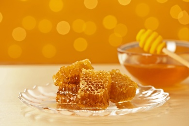 Photo of Plate with fresh honeycombs on table against blurred background