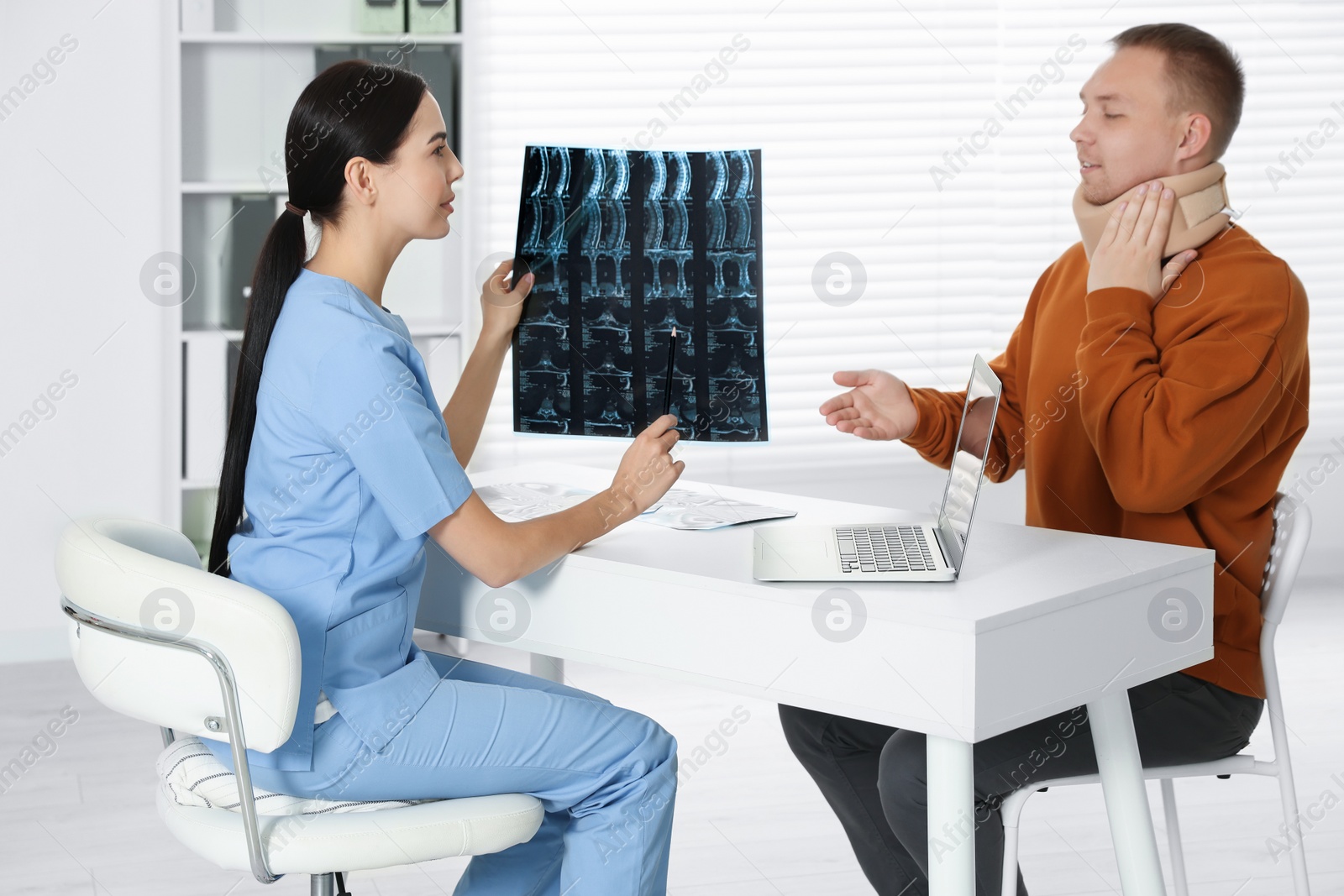 Photo of Doctor with neck MRI image consulting patient in clinic