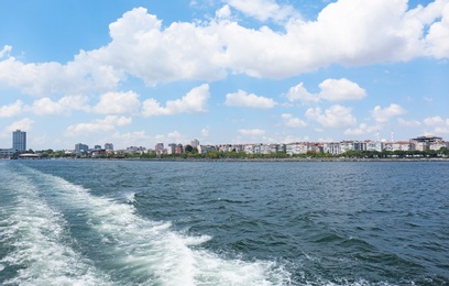 Photo of Boat track on sea surface and beautiful view of city on shore
